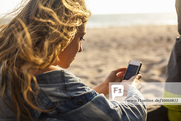 Frau mit Smartphone am Strand