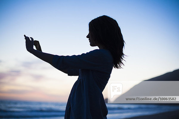 Frau nimmt Selfie am Strand bei Sonnenuntergang  Malibu  Kalifornien  USA