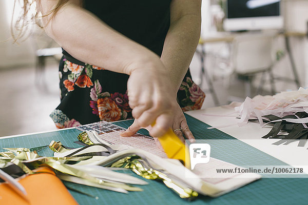 Close up of female textile designer cutting textiles in design studio
