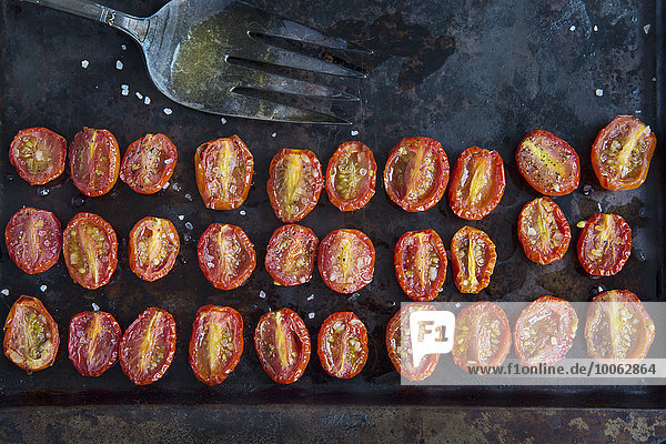 Überkopfansicht von Reihen halbierter gerösteter Tomaten auf Backblech
