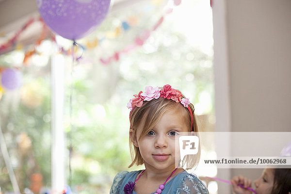 Portrait of blonde girl with flower headband smiling at camera