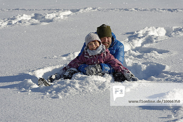 Father and daughter sitting in the deep snow  Bad Heilbrunn  Upper Bavaria  Bavaria  Germany  Europe