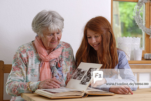 Enkelin und Großmutter schauen ein Fotoalbum an  Bayern  Deutschland  Europa