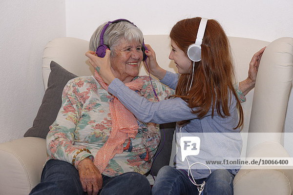 Enkelin und Großmutter hören Musik über Kopfhörer  digitale Musik  Bayern  Deutschland  Europa
