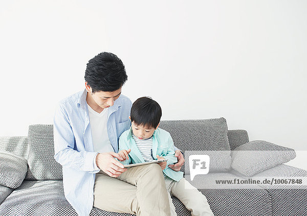 Japanese father and son on the sofa with tablet