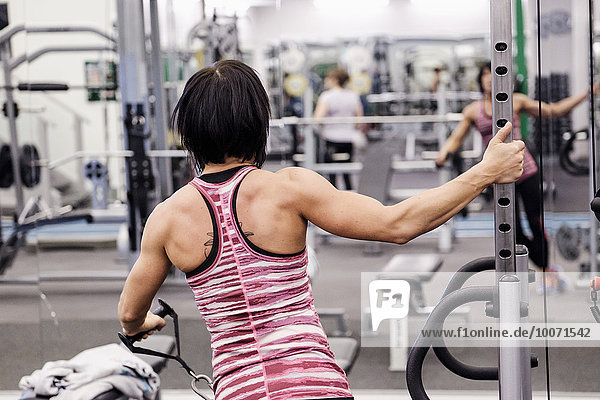 Rückansicht der Sportlerin beim Training im Fitnessstudio