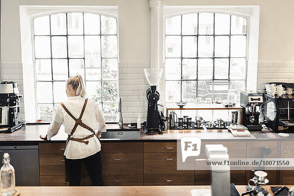 Rückansicht der weiblichen Barista bei der Arbeit am Cafe Counter