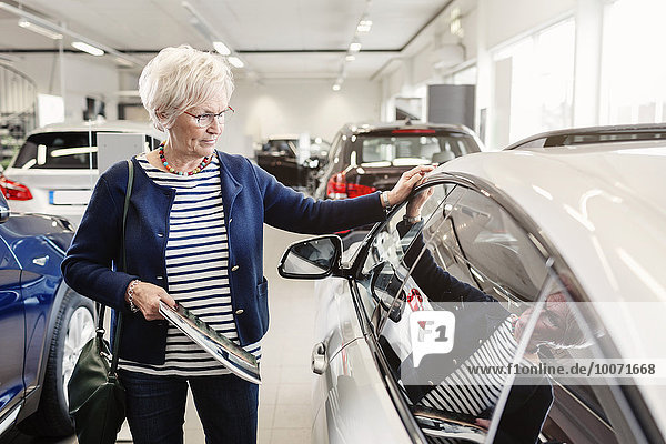 Seniorin bewundert Auto im Autohaus