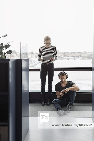 Geschäftsleute  die Technologien per Fenster im Büro nutzen