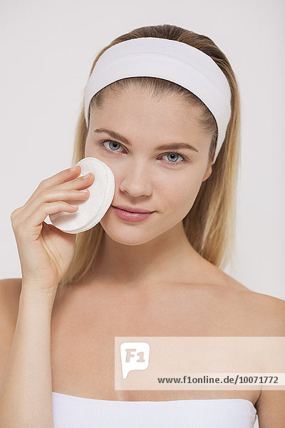 Frau putzt ihr Gesicht mit einem Wattebausch