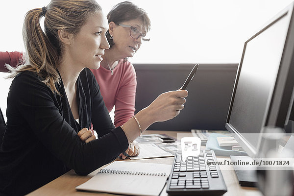 Geschäftsfrauen diskutieren über Computer am Schreibtisch im Büro