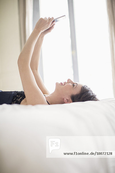 Woman lying on the bed using a mobile phone