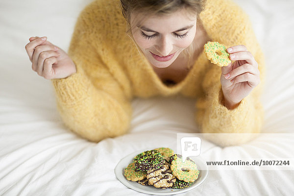 Woman eating a cookie on bed