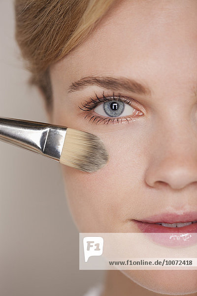 Beautiful woman applying make-up with blusher