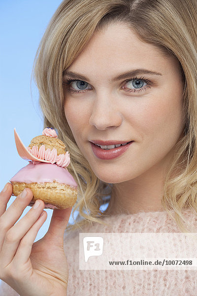 Portrait of a beautiful woman holding a french strawberry religieuse