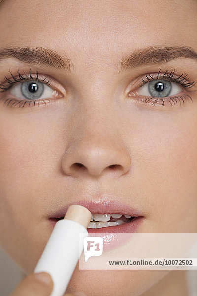 Beautiful woman applying lip balm