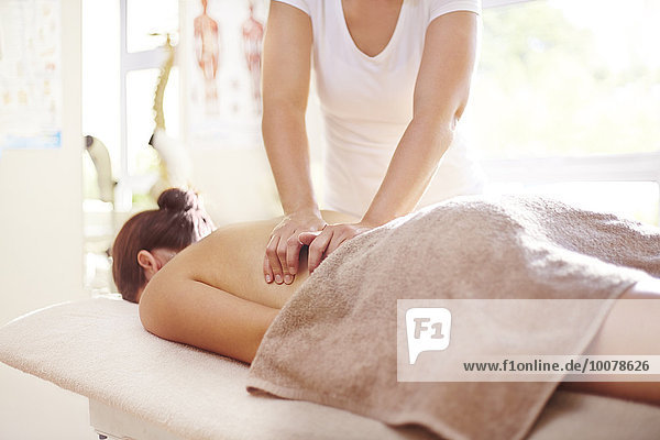 Frau erhält Massage durch Masseurin