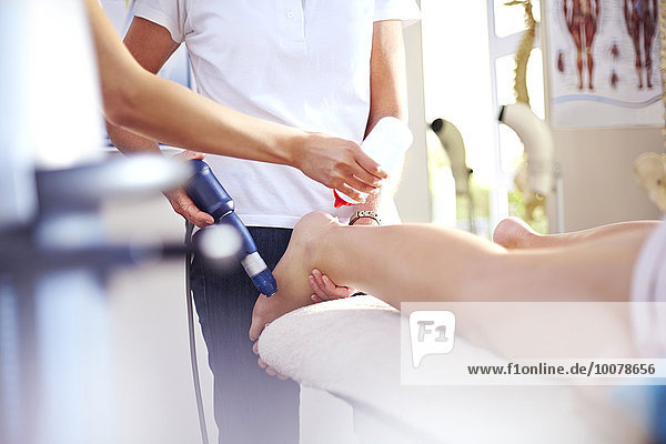 Masseurin beim Auftragen des Gels auf das Bein der Frau zur Vorbereitung der Ultraschallsonde