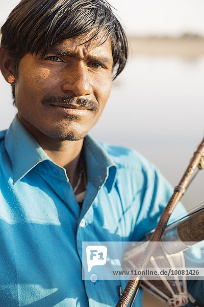 Close up of Indian man holding traditional instrument