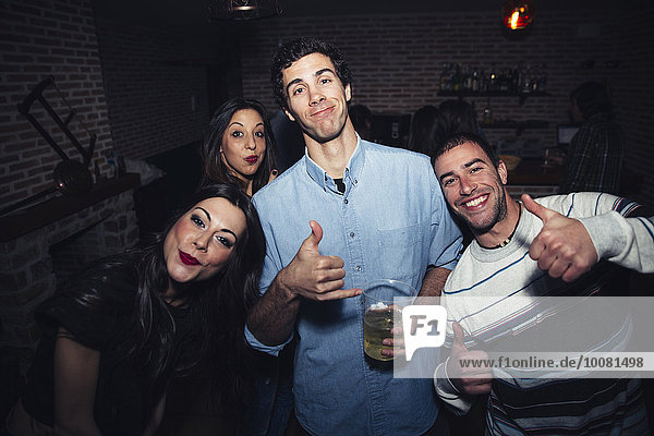 Laughing friends giving thumbs up in nightclub