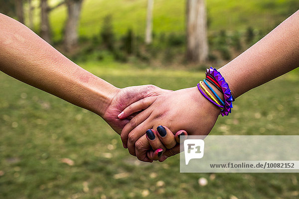 Close up of women holding hands in park
