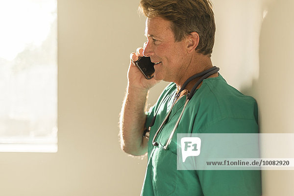 Caucasian nurse talking on cell phone near window