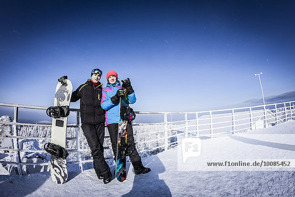 Caucasian snowboarders standing on mountaintop