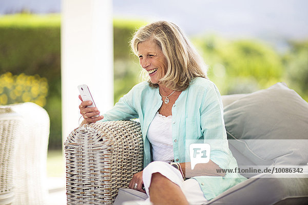 Caucasian woman using cell phone on sofa outdoors