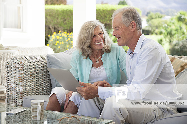 Caucasian couple using laptop on sofa outdoors