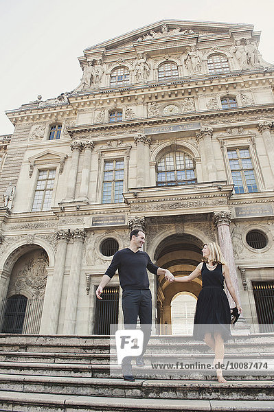 Caucasian couple walking on ornate building steps  Paris  Ile-de-France  France