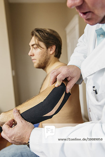Caucasian doctor applying tape to elbow of patient