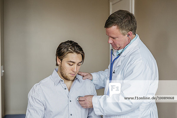 Caucasian doctor listening to heartbeat of patient