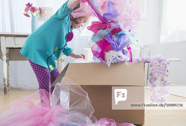 Caucasian girl unpacking dress-up clothes from box