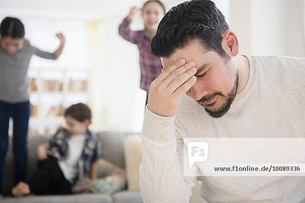Stressed Caucasian father with shouting children in living room