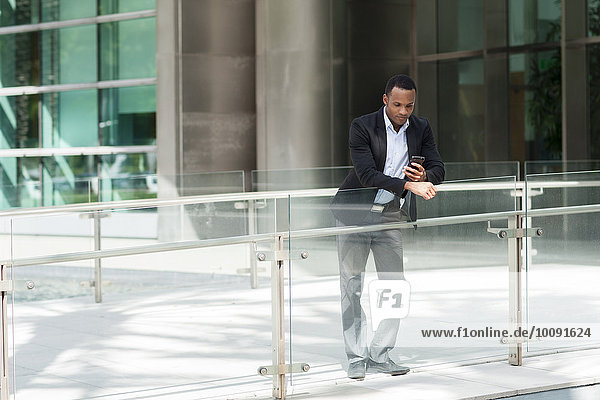 Black businessman using cell phone outside building