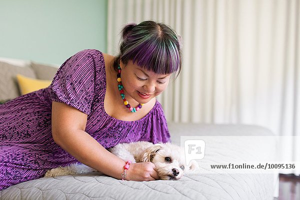 Mittlere erwachsene Frau auf dem Bett liegend mit Hund