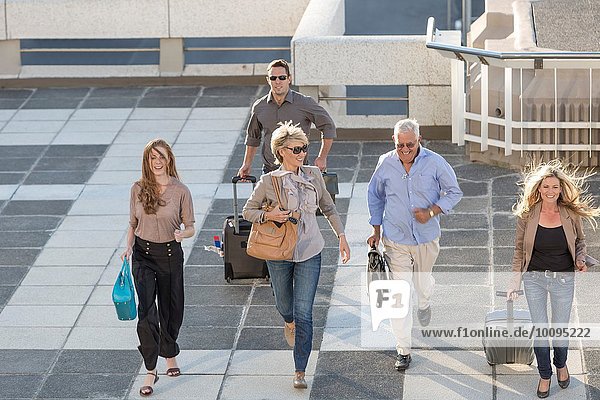 Five adults walking across paving slabs