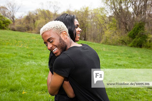 Two young men hugging in park