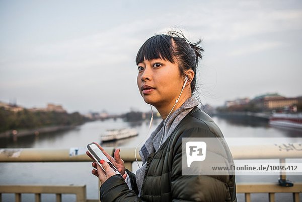 Porträt einer Frau vor dem Fluss mit Kopfhörern