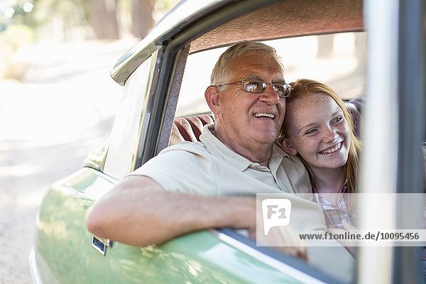 Grandfather and granddaughter sitting in back seat of car  smiling