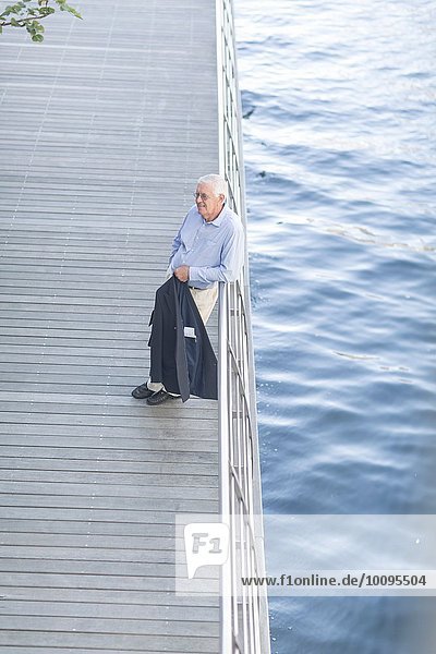 Senior businessman leaning against hotel terrace railings