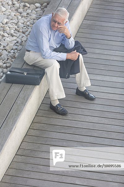High angle view of senior businessman sitting alone on hotel terrace