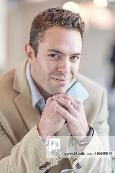 Portrait of mid adult businessman holding smartphone