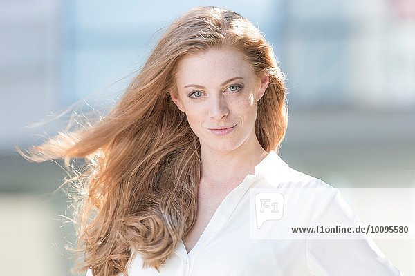 Portrait of beautiful young woman with long red flyaway hair