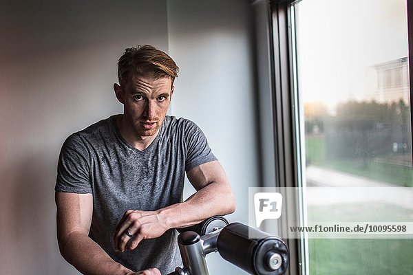 Portrait of sweaty mid adult man leaning on exercise machine in gym