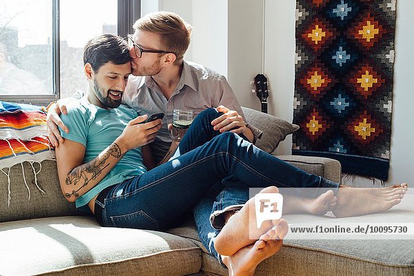 Male couple relaxing on sofa together