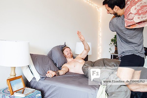 Male couple having pillow fight  laughing