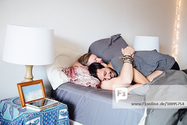 Männliches Paar auf dem Bett  umarmend  lächelnd