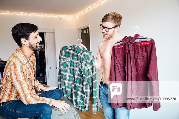 Männliches Paar  mittlerer erwachsener Mann  der um Hilfe bei der Auswahl des Hemdes bittet.
