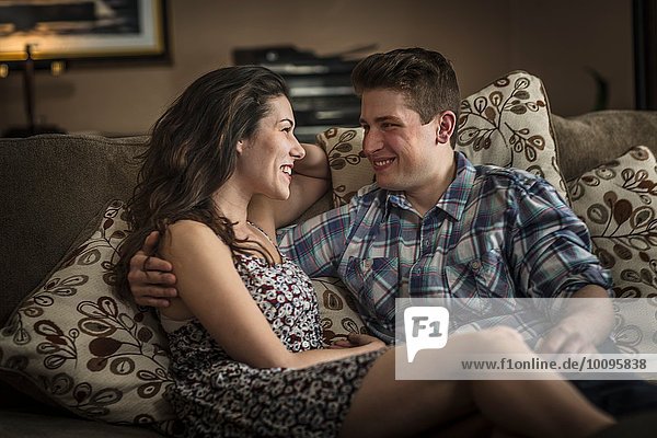 Romantic young couple reclining on living room sofa